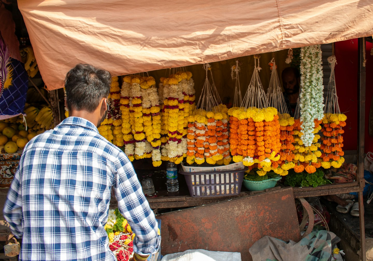 Customer at a roadside flower shop with marigold garlands in Kamshet, Maharashtra