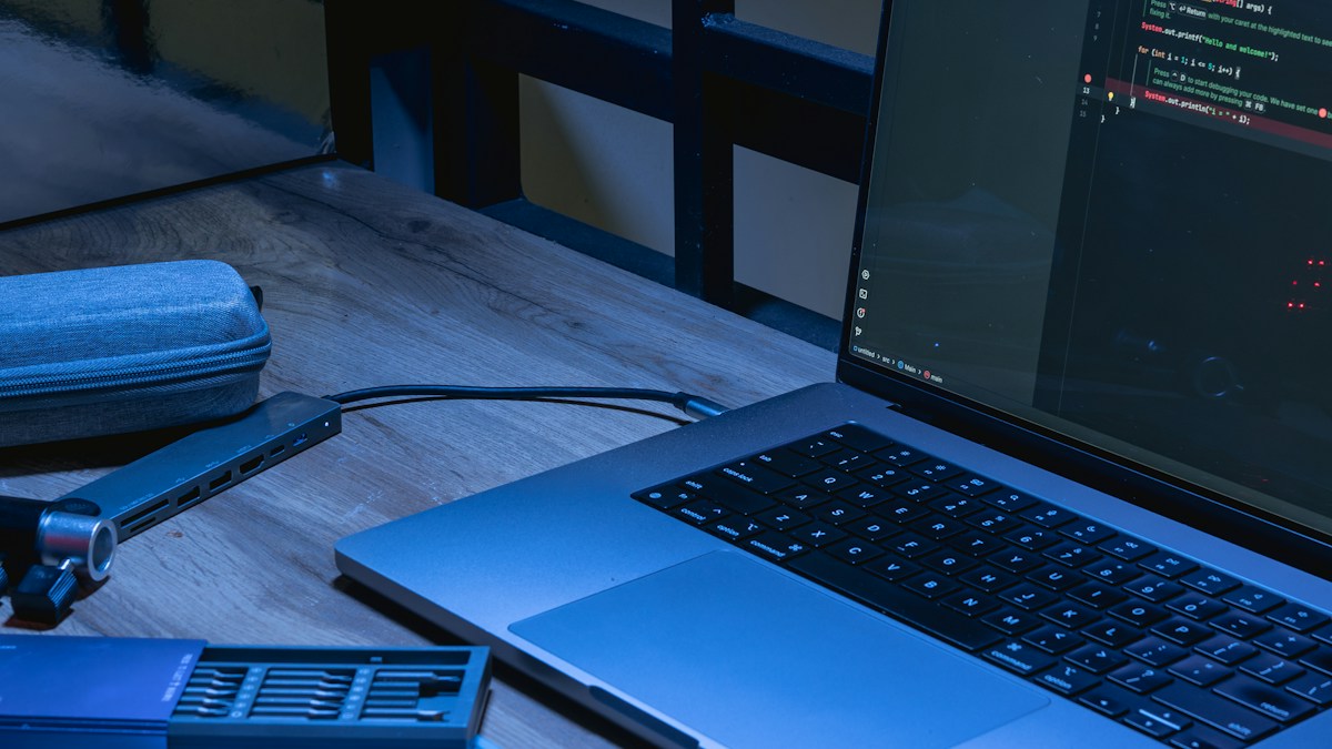 A laptop displaying source code on a blue-lit desk