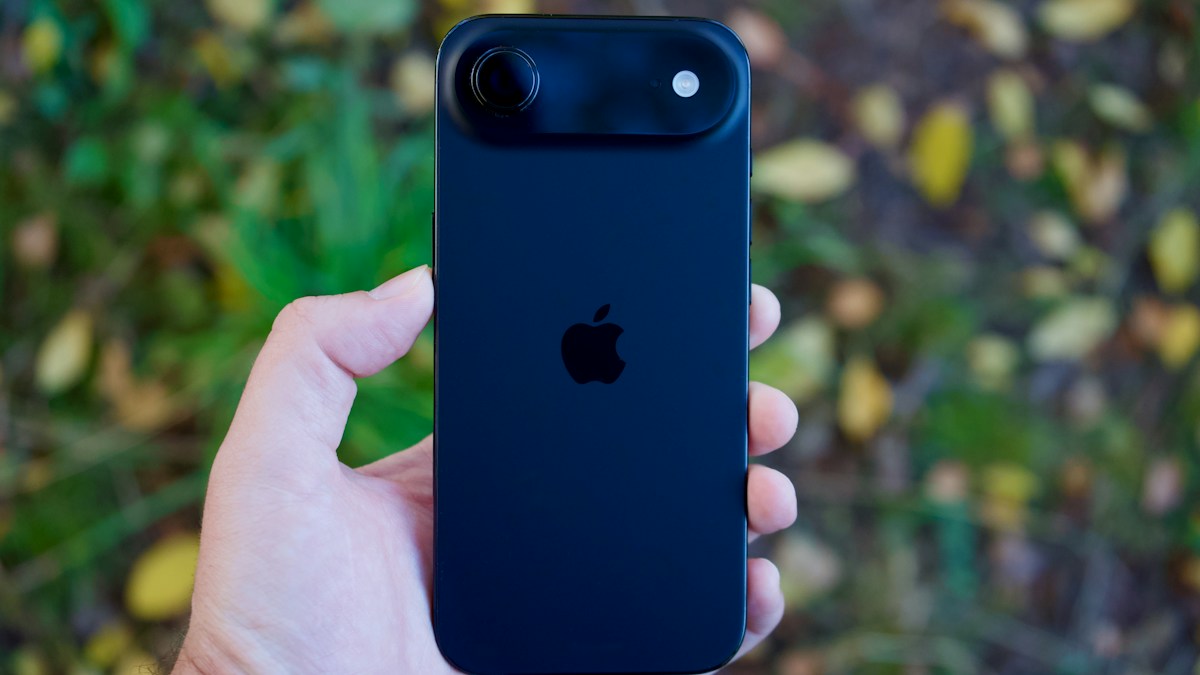 Hand holding a black iPhone Air outdoors