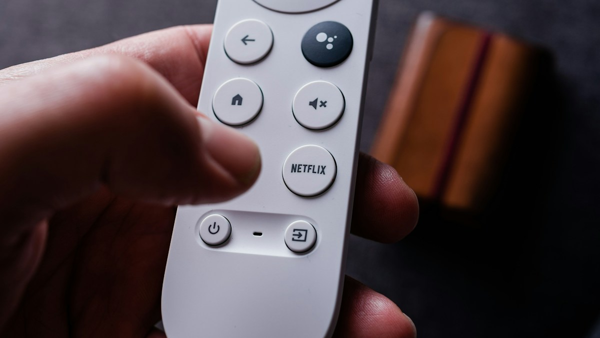 Hand holding a television remote with a Netflix button