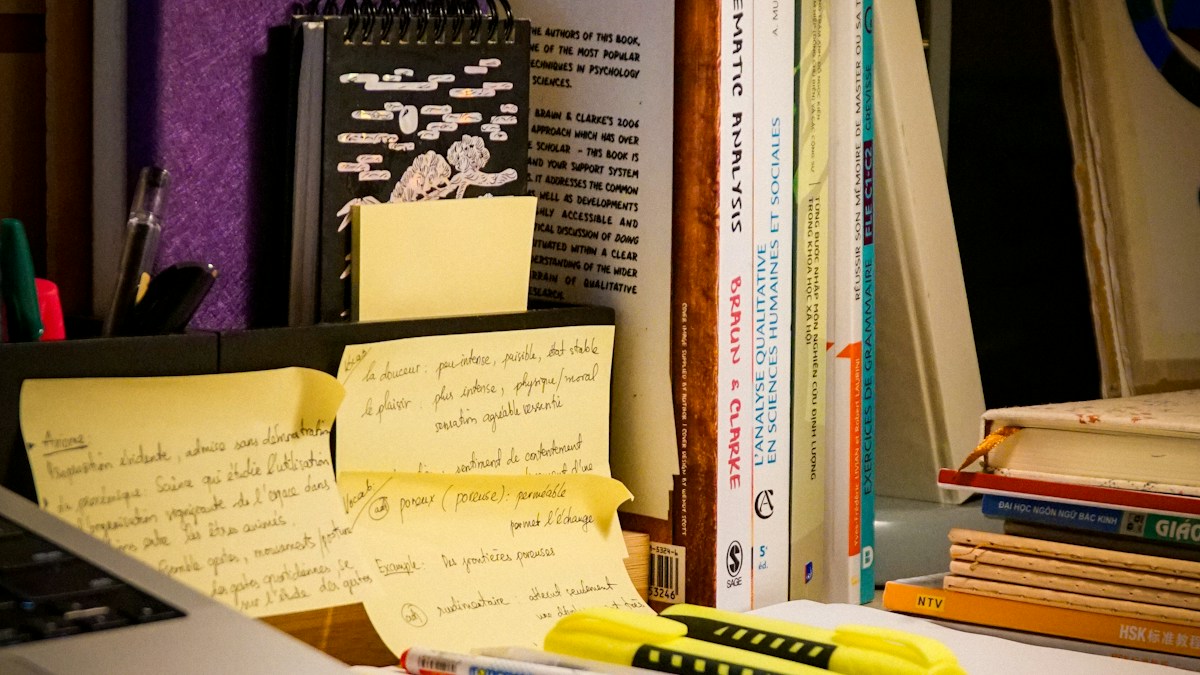 Books, handwritten notes and study materials beside a laptop